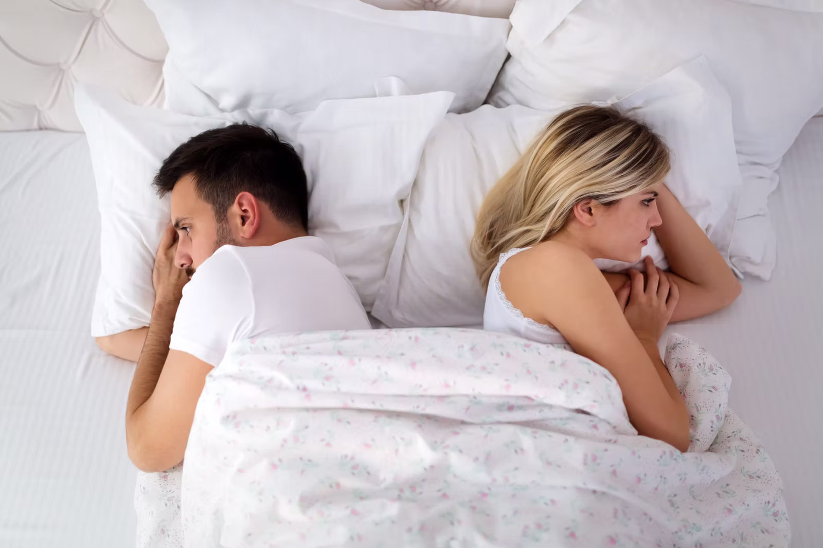 Paar liegt voneinander abgewandt im Bett